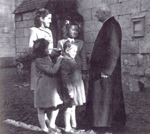 Jacqueline et Nicole (au second plan), Jeannette et Laura (au premier plan) avec le chanoine Ségelle, dans la cour du presbytère.