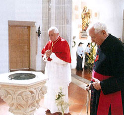 Benoît XVI près des fonts baptismaux où il a été baptisé. À sa gauche, son frère Georges.